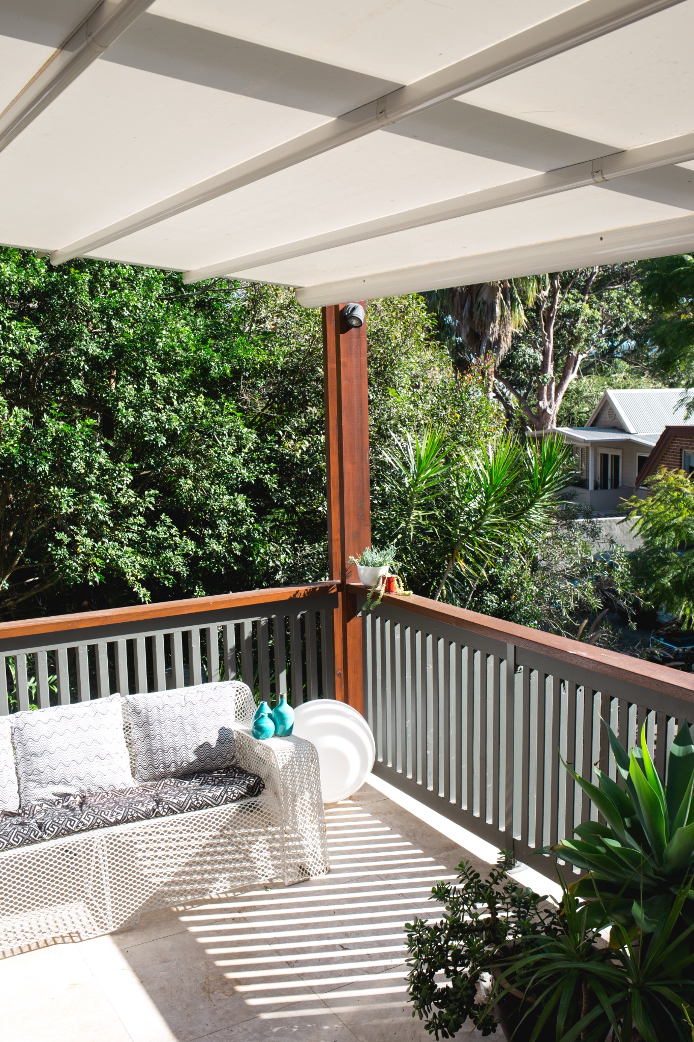 Duet roof fully extended to protect a leafy balcony from rain and sun