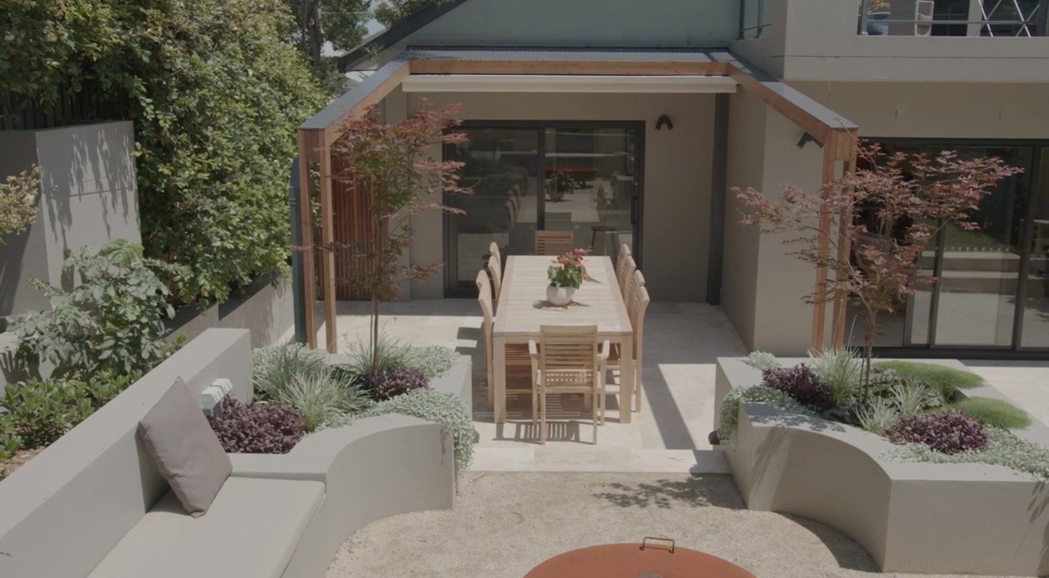 Duet roof fully retracted above a landscaped outdoor dining area